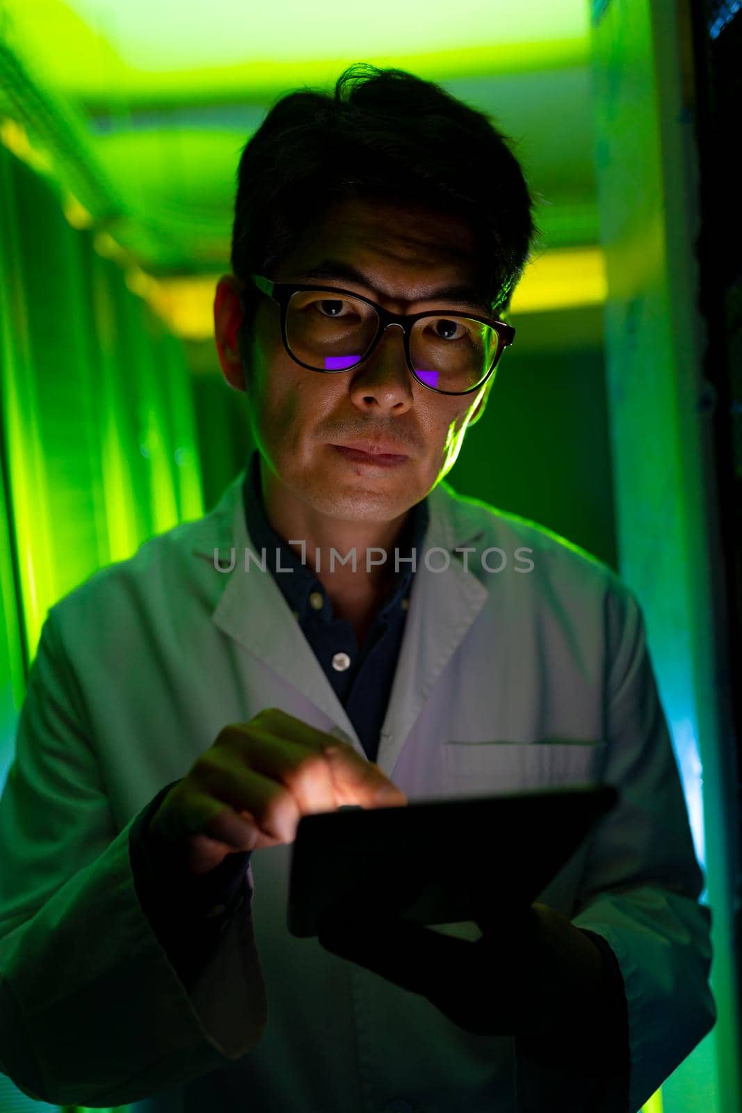 Portrait of asian male engineer wearing an apron using digital tablet in computer server room. database server management and maintenance concept