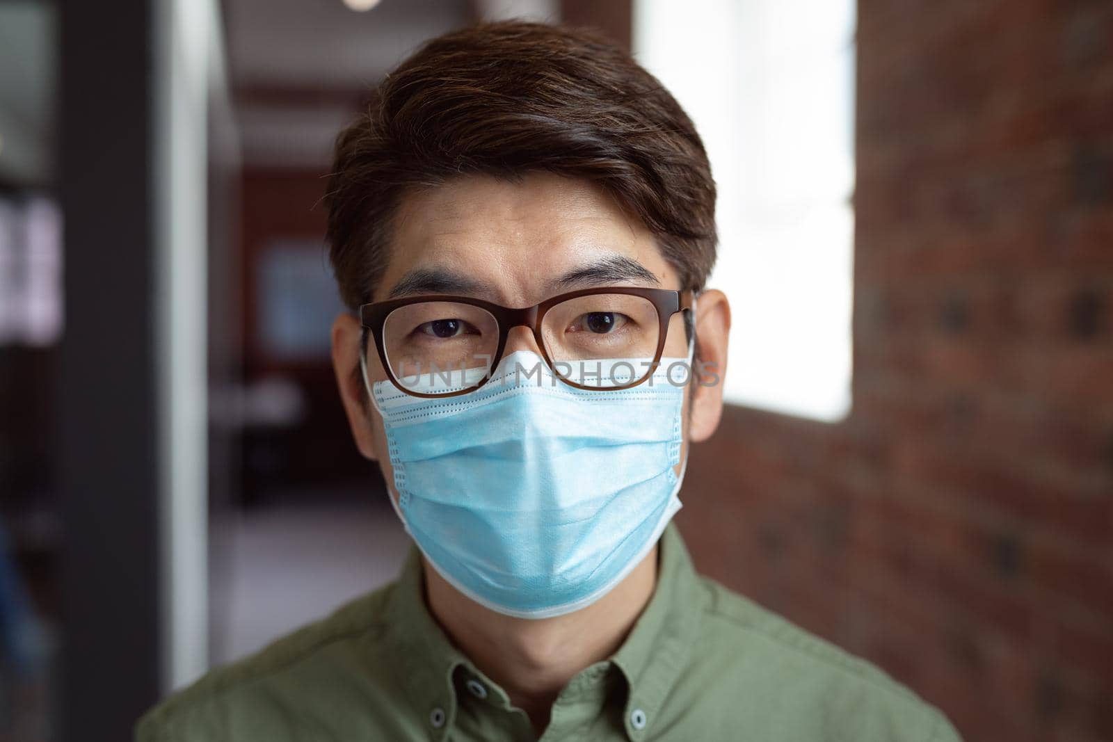 Portrait of asian businessman wearing face mask in office looking to camera. working in business at a modern office during coronavirus covid 19 pandemic. sian