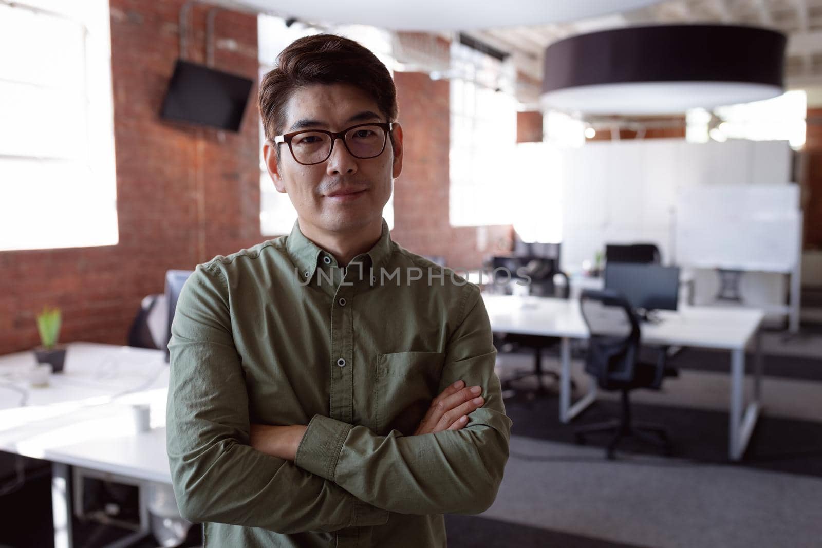 Portrait of serious asian businessman standing in office with arms crossed looking to camera by Wavebreakmedia