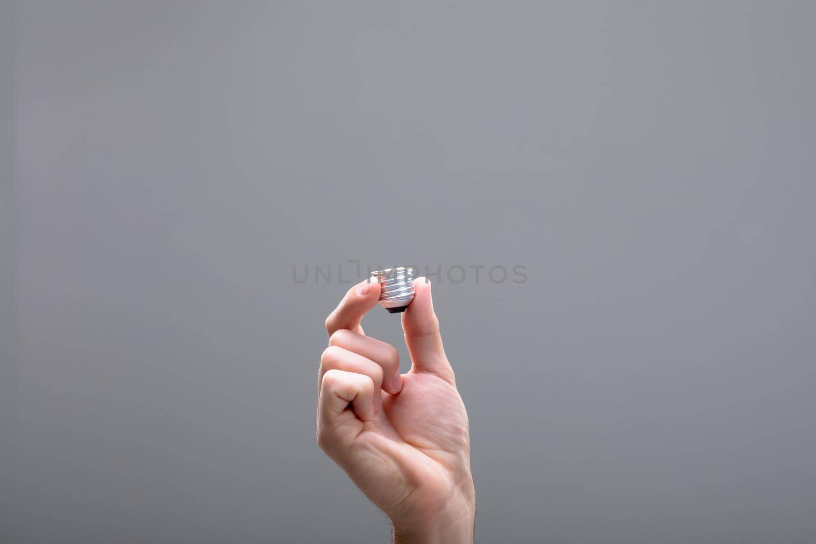 Close up of caucasian businessman holding base of light bulb, isolated on grey background. business technology, communication and growth concept.