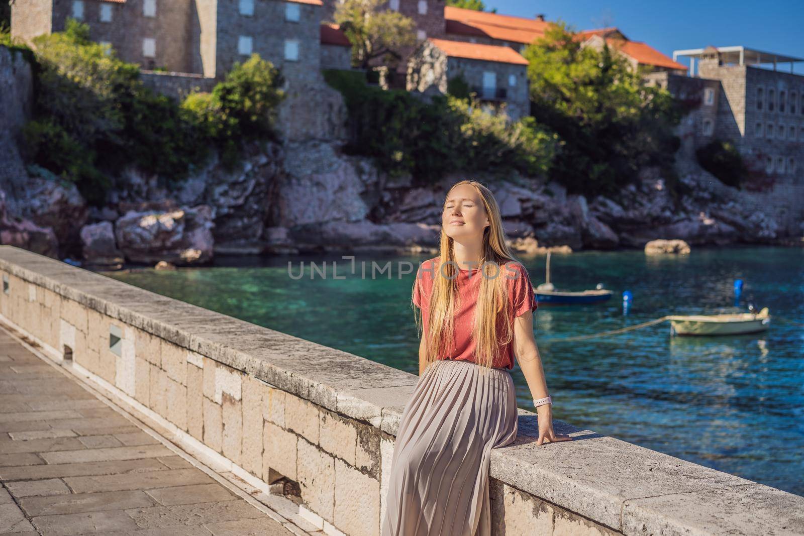 Woman tourist on background of beautiful view of the island of St. Stephen, Sveti Stefan on the Budva Riviera, Budva, Montenegro. Travel to Montenegro concept.