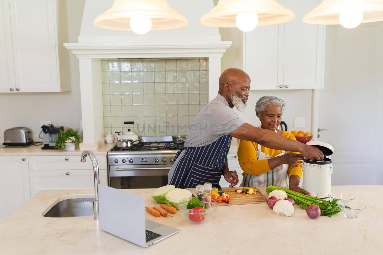 Senior african american couple cooking together in kitchen. retreat, retirement and happy senior lifestyle concept.