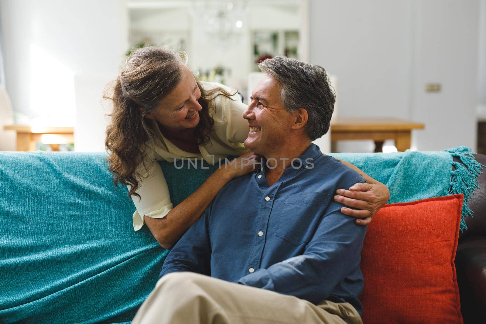 Happy senior caucasian couple in living room sitting on sofa, embracing. retirement lifestyle, spending time at home.
