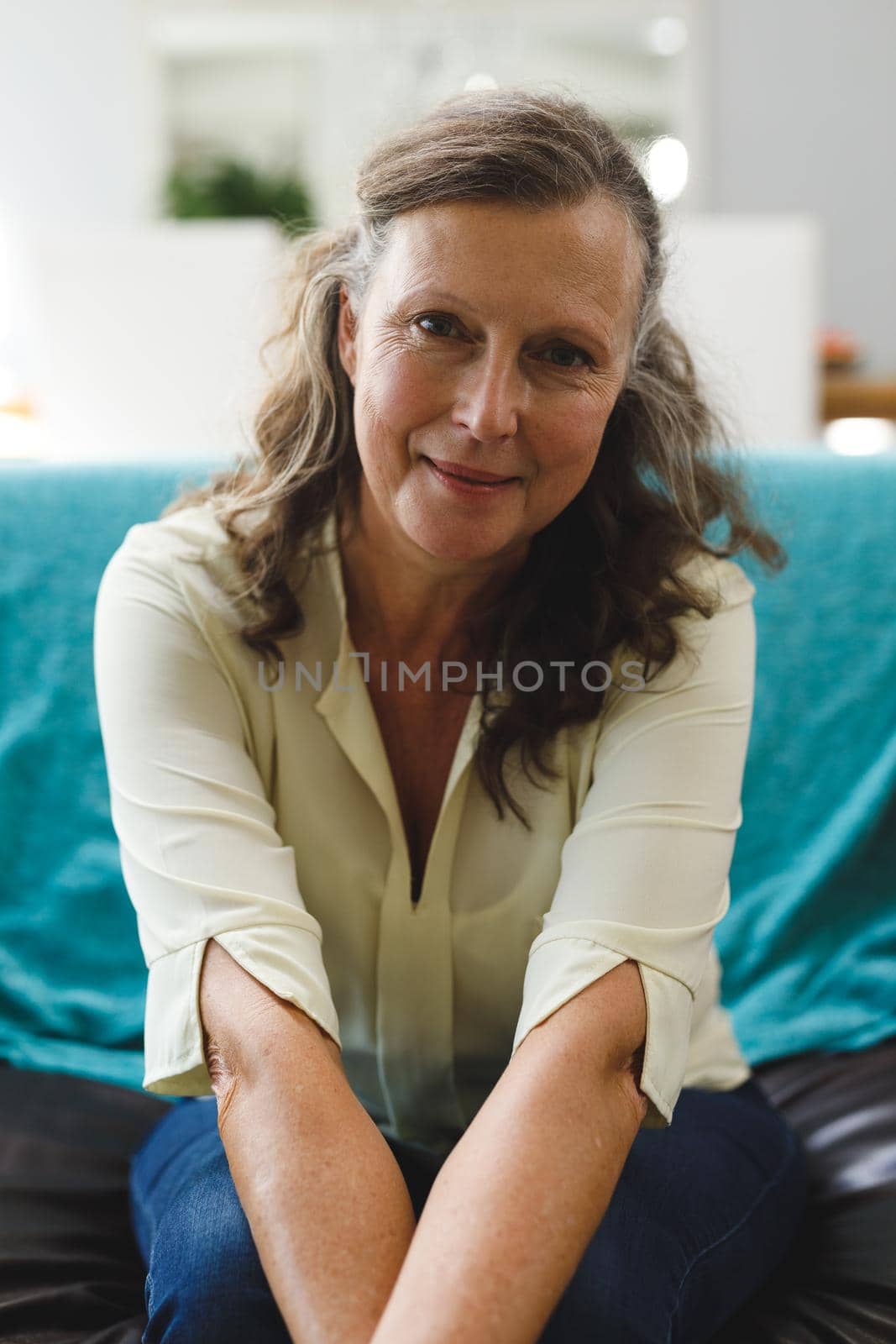 Portrait of happy senior caucasian woman in living room sitting on sofa, looking to camera. retirement lifestyle, spending time at home.