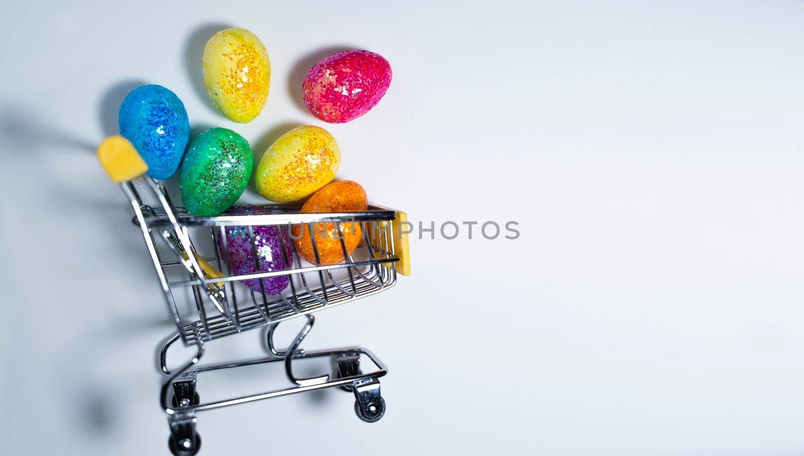 Happy Easter background. Easter colorful eggs in a shopping basket on a white background. Holiday concept. Copy space for text