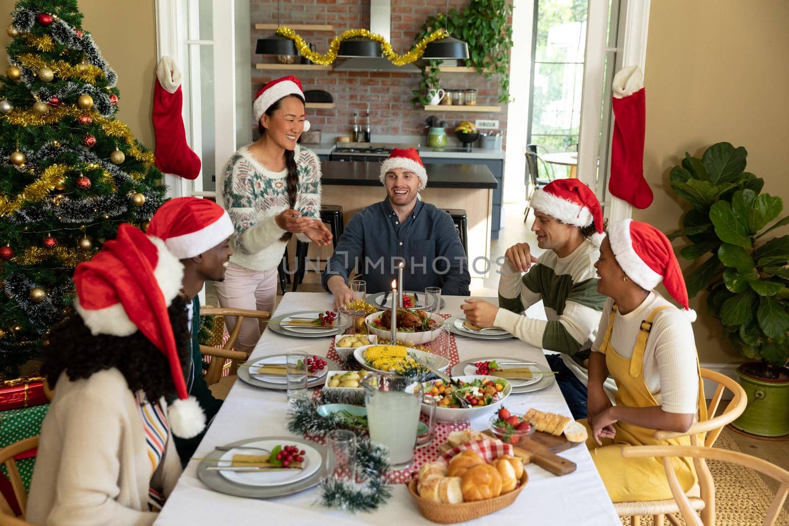 Group of happy diverse female and male friends having christmas meal together at home. christmas festivities, celebrating at home with friends