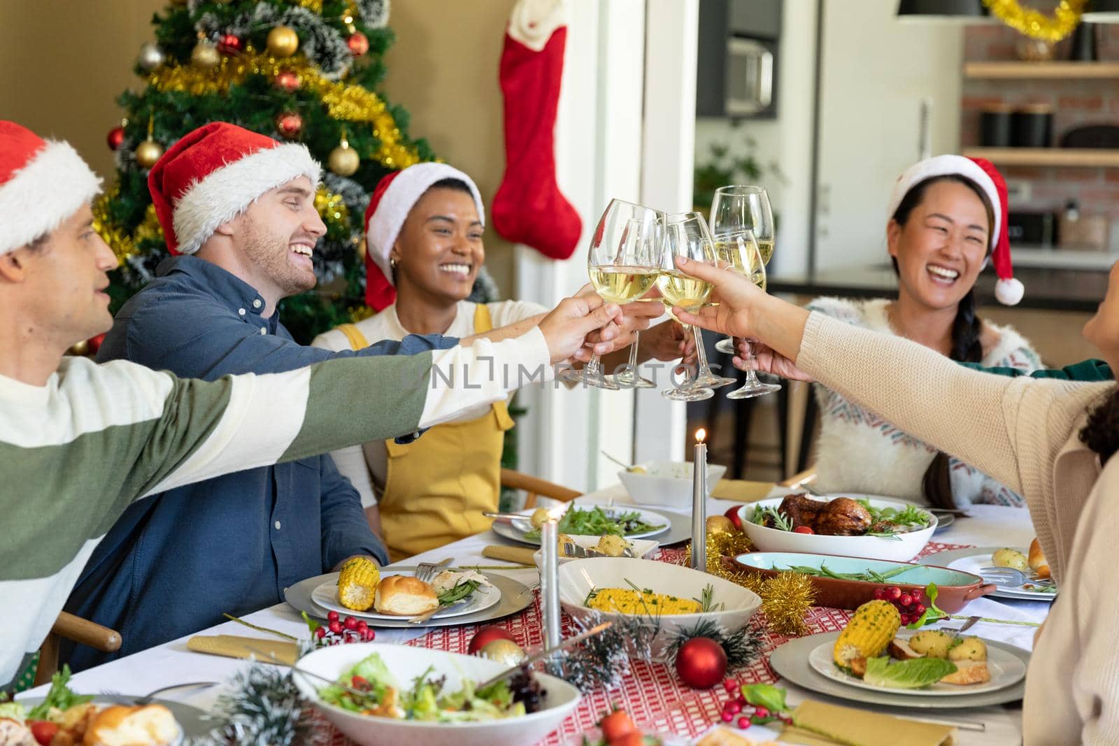 Group of happy diverse female and male friends toasting, celebrating christmas at home by Wavebreakmedia