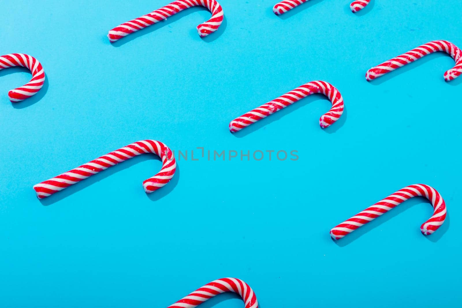 Composition of rows of multiple candy canes on blue background. christmas, tradition and celebration concept.