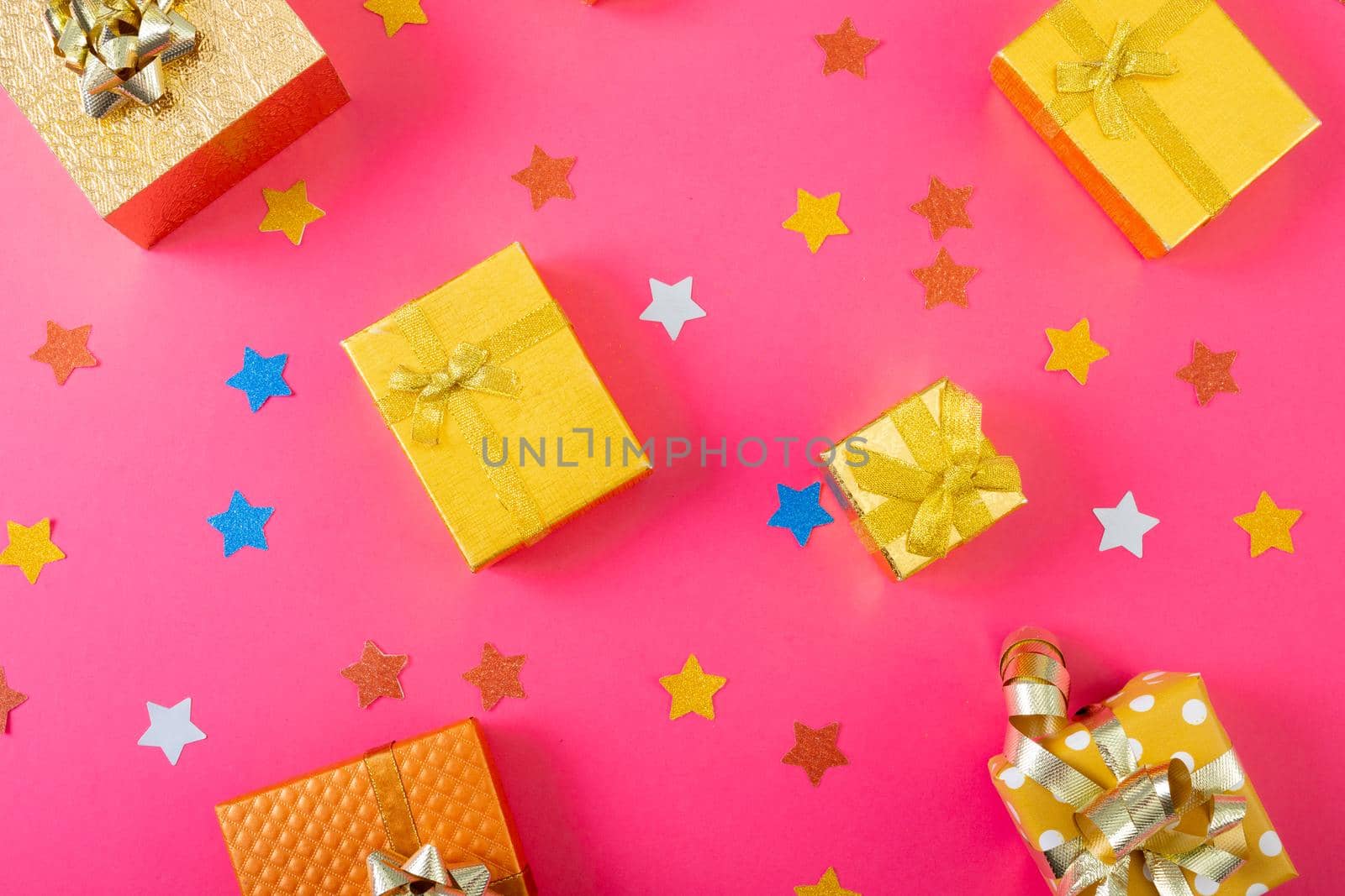 Composition of christmas decorations with presents and stars on pink background. christmas, tradition and celebration concept.
