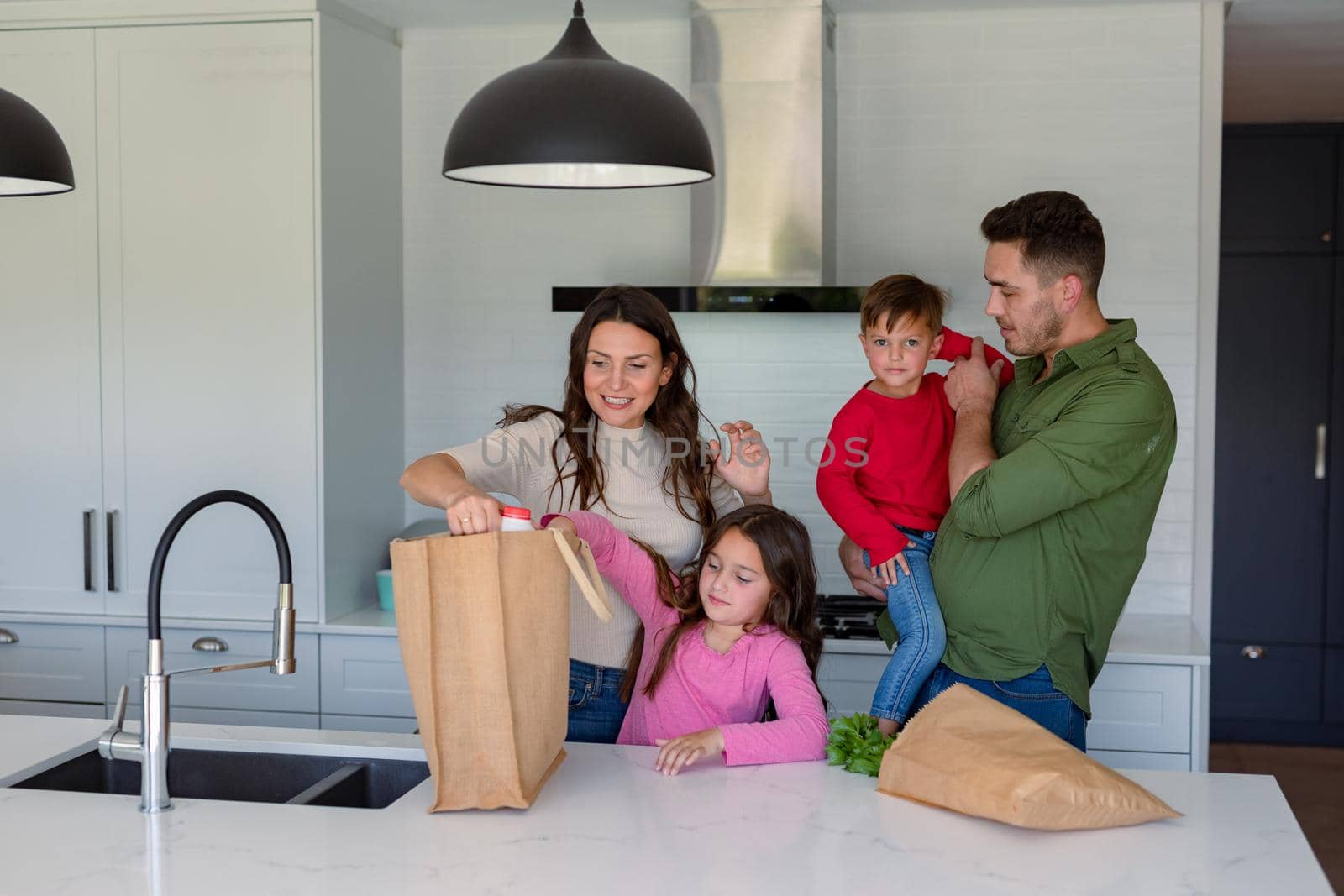 Happy caucasian family unpacking groceries together in kitchen. family time, having fun together at home.