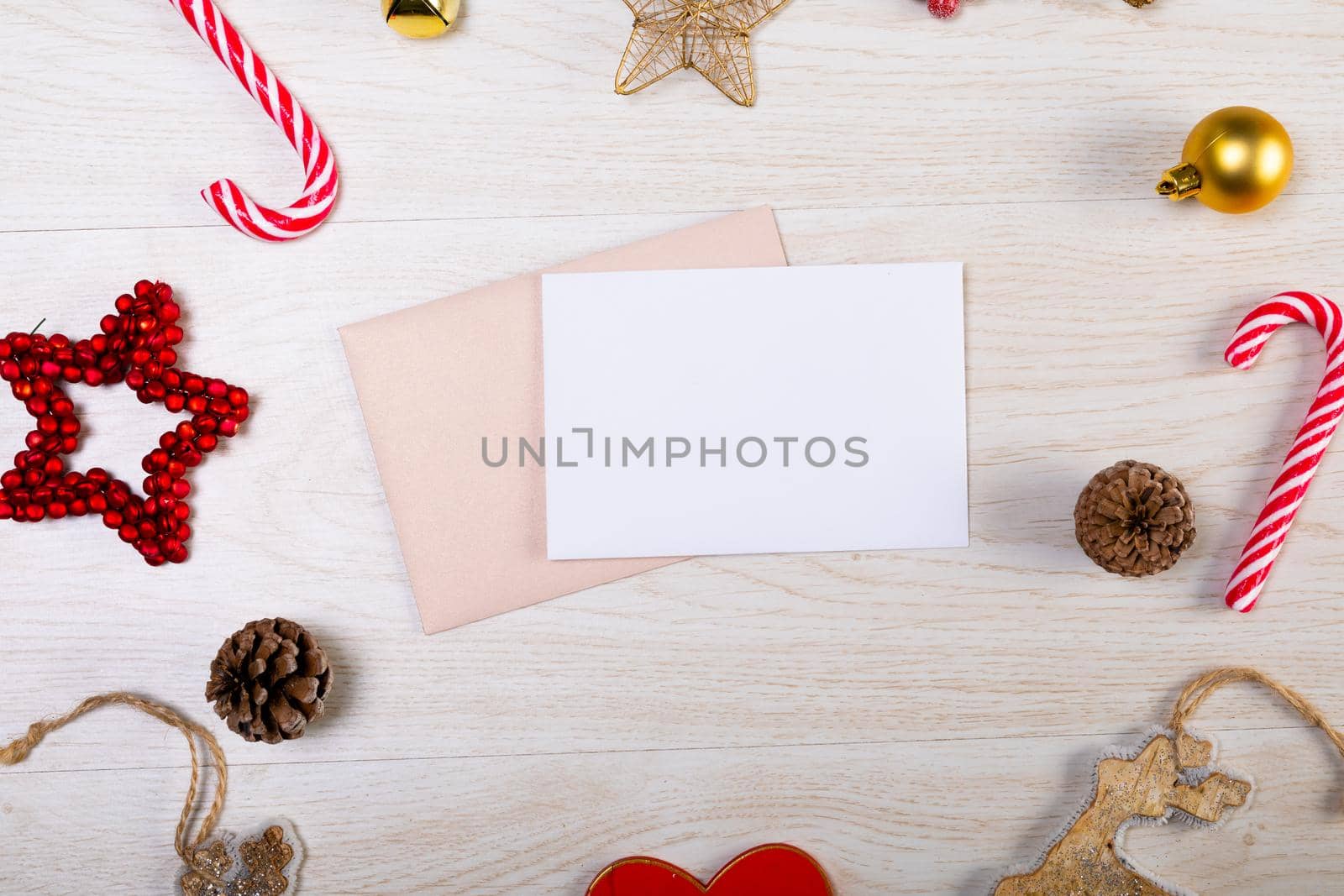 Composition of white card with copy space, envelope and christmas decorations on wooden background. christmas, tradition and celebration concept.