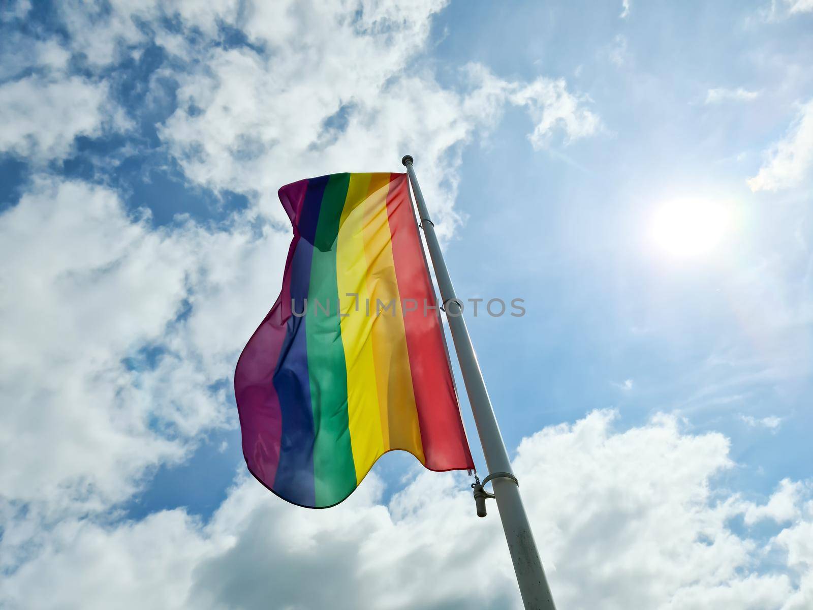 Rainbow pride flag illustration. Lgbt community symbol in rainbow colors against the blue sky 