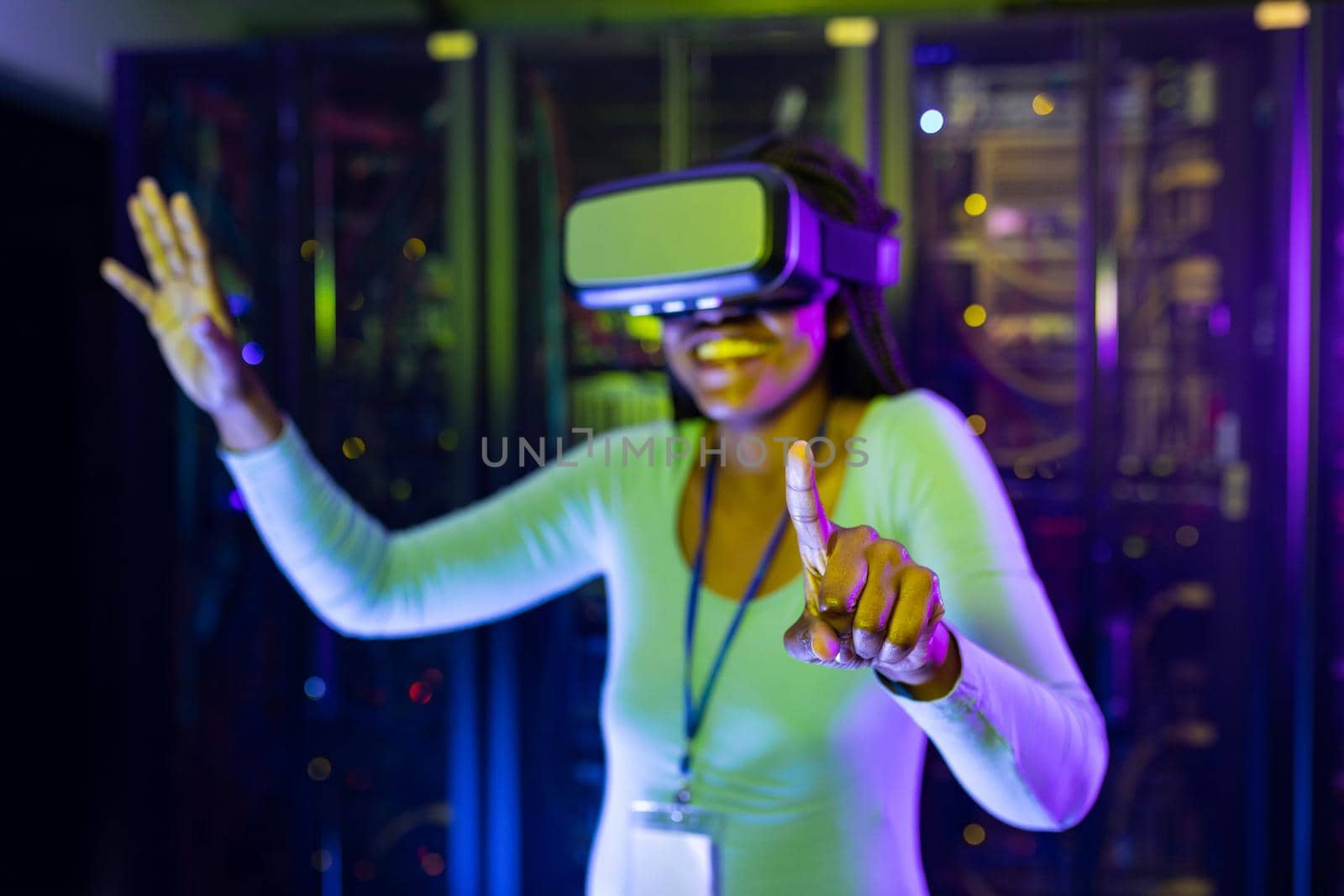 Happy african american female computer technician wearing vr headset and working in server room by Wavebreakmedia