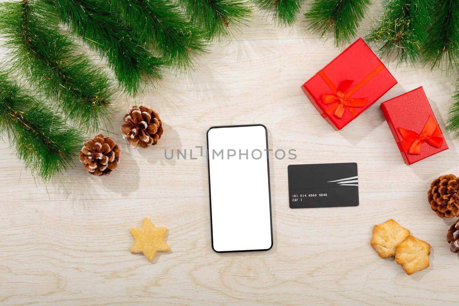 Composition of smartphone with copy space, card and christmas decorations on wooden background. christmas, communication, tradition and celebration concept.