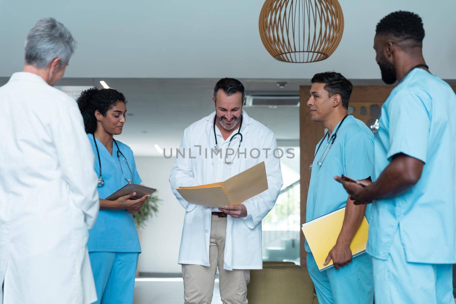 Diverse male and female doctors standing in hospital corridor and discussing by Wavebreakmedia
