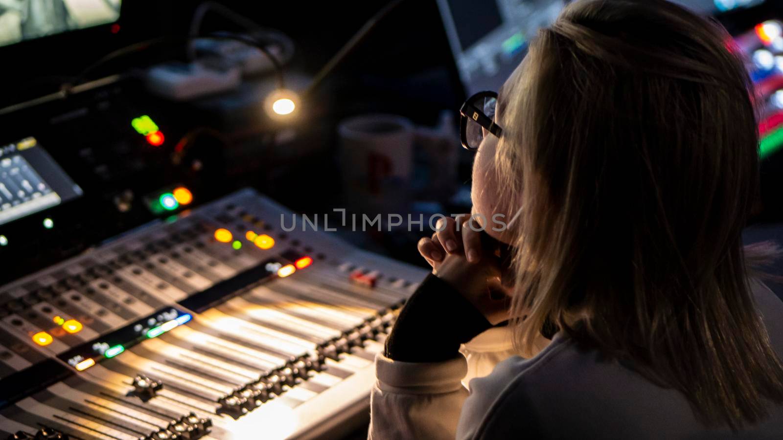 Russia October 2020. the girl sound engineer works works on the broadcast at the sound console. low light