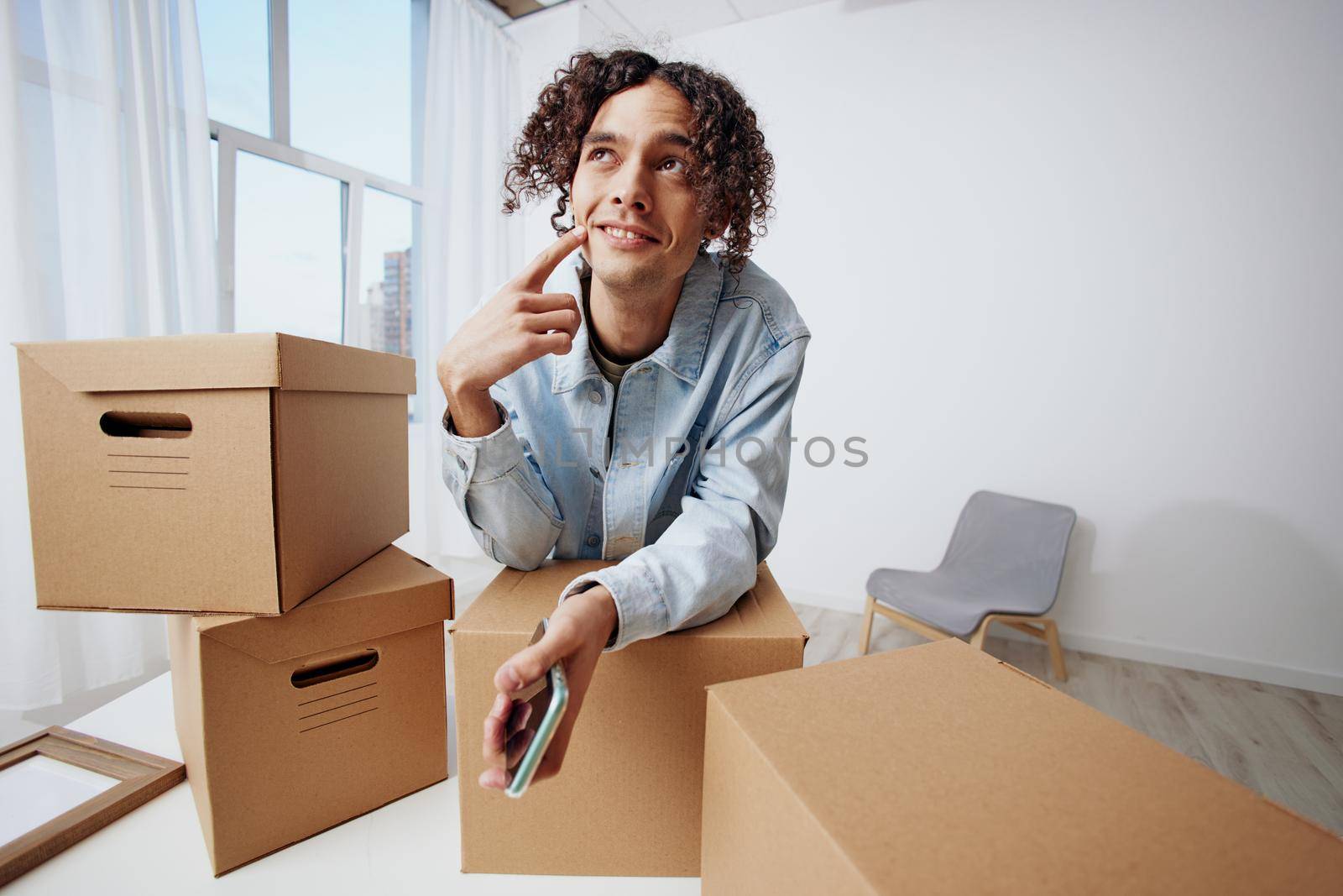 portrait of a man cardboard boxes in the room unpacking with phone sorting things out. High quality photo