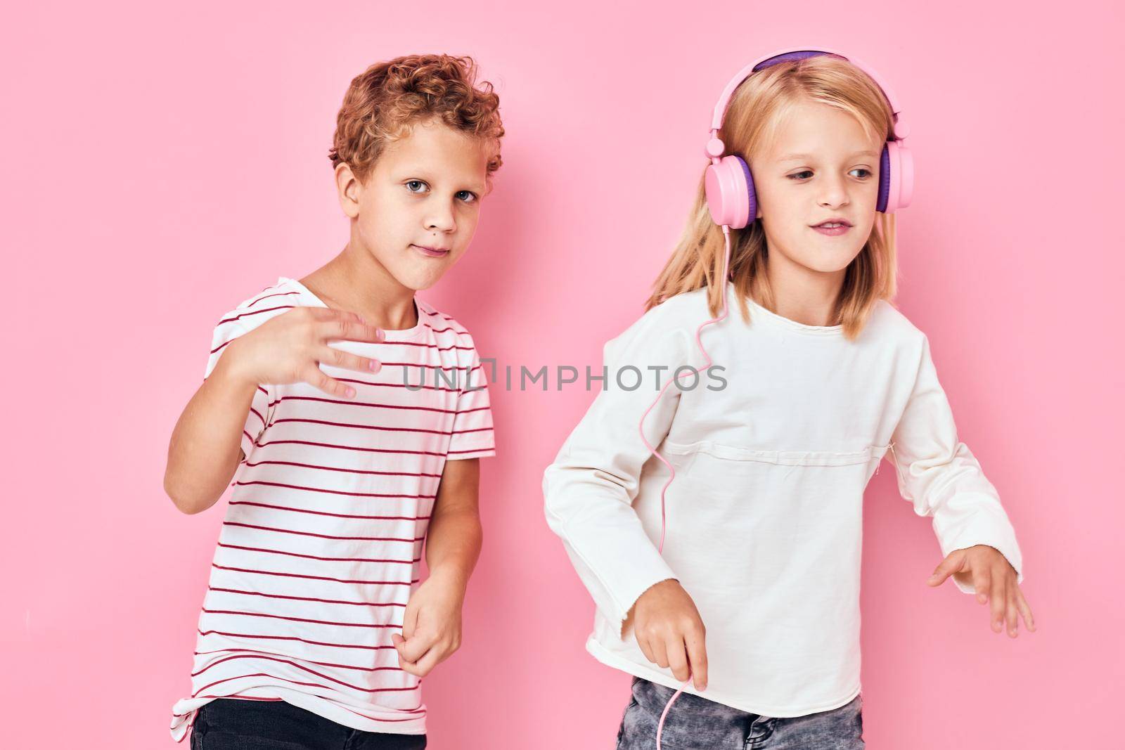 boy and girl wearing headphones entertainment music pink background. High quality photo