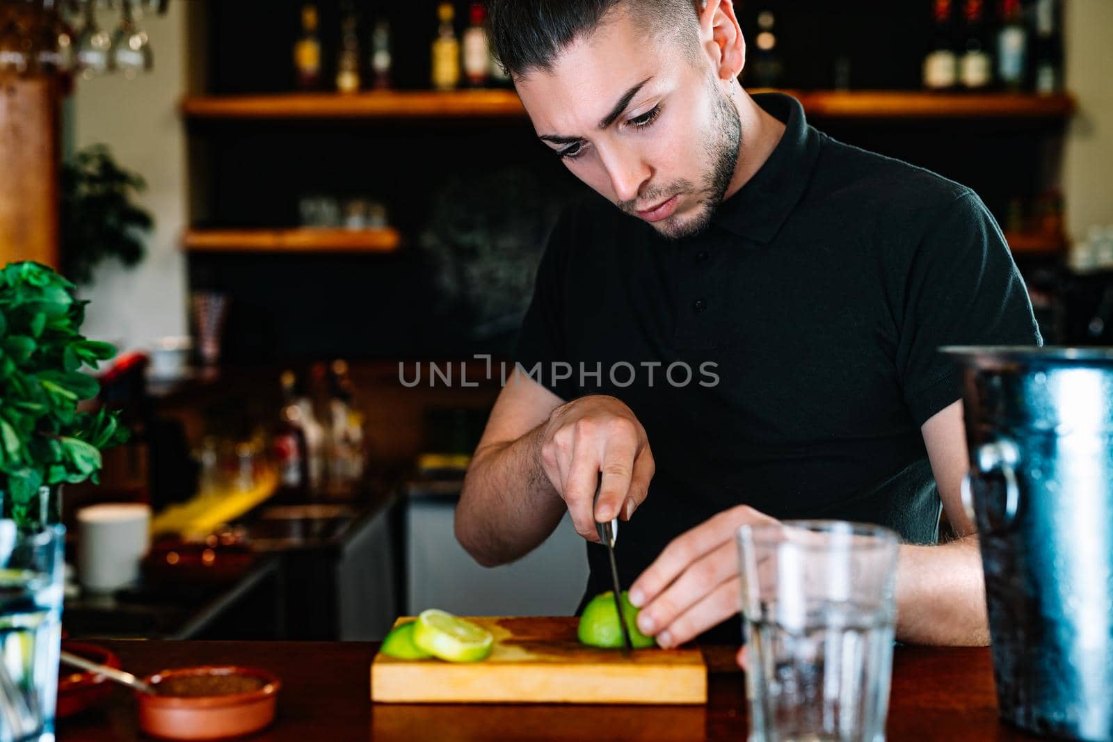 young waiter cutting slices of citrus fruit to prepare a mixed drink. Prepare a Mojito by CatPhotography