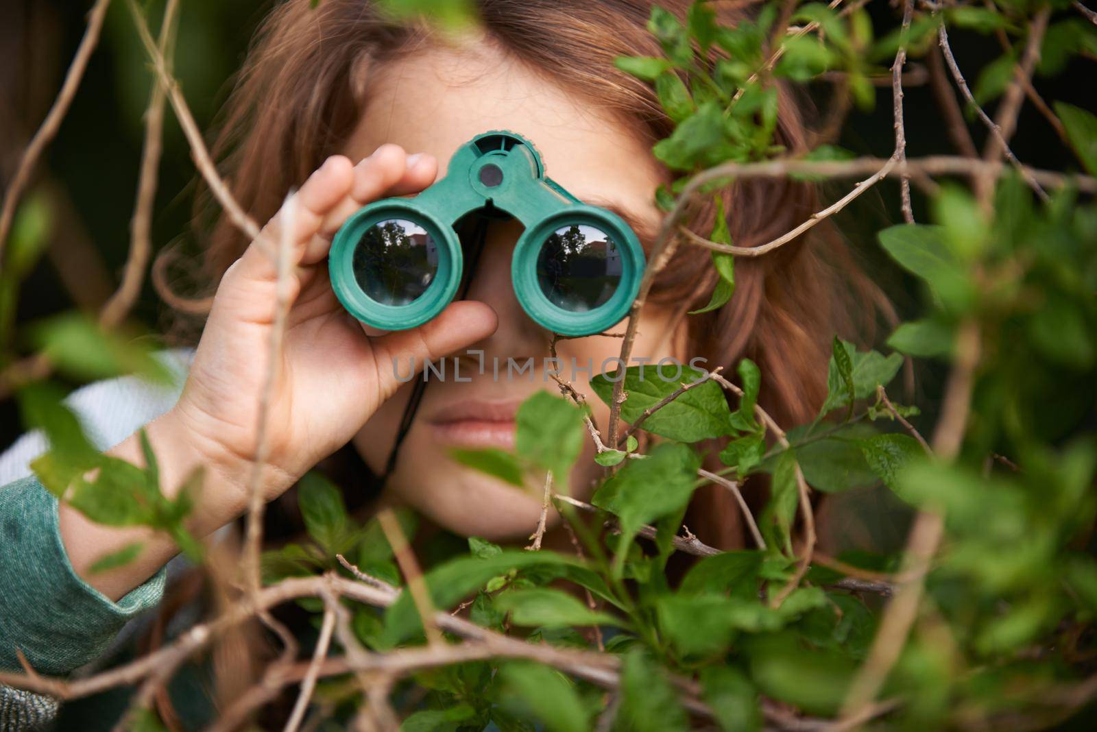 Bird watching is serious. Shot of a cute little girl looking through a pair of binoculars outdoors. by YuriArcurs
