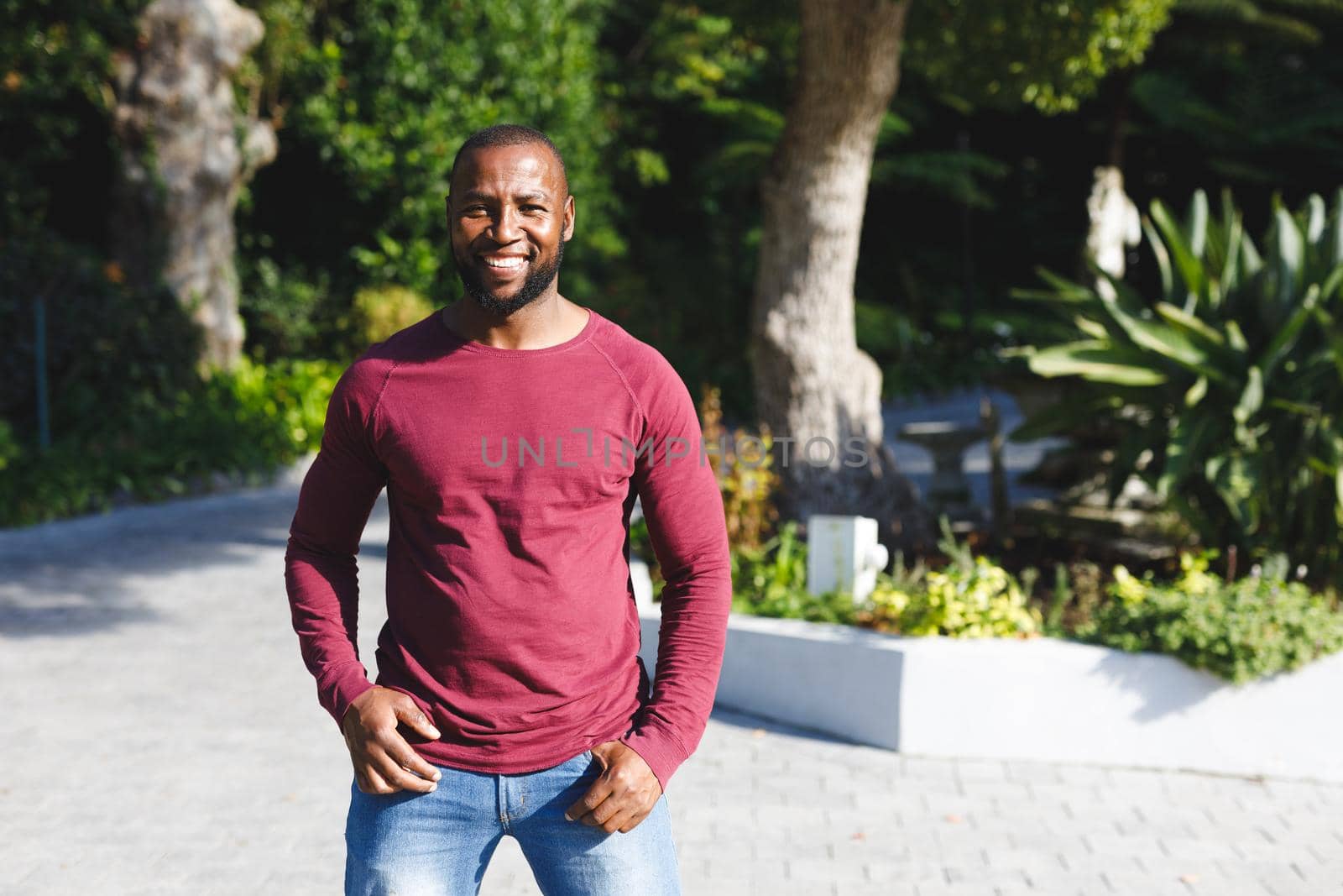 Portrait of african american man smiling and looking at camera in sunny garden. spending time alone at home.