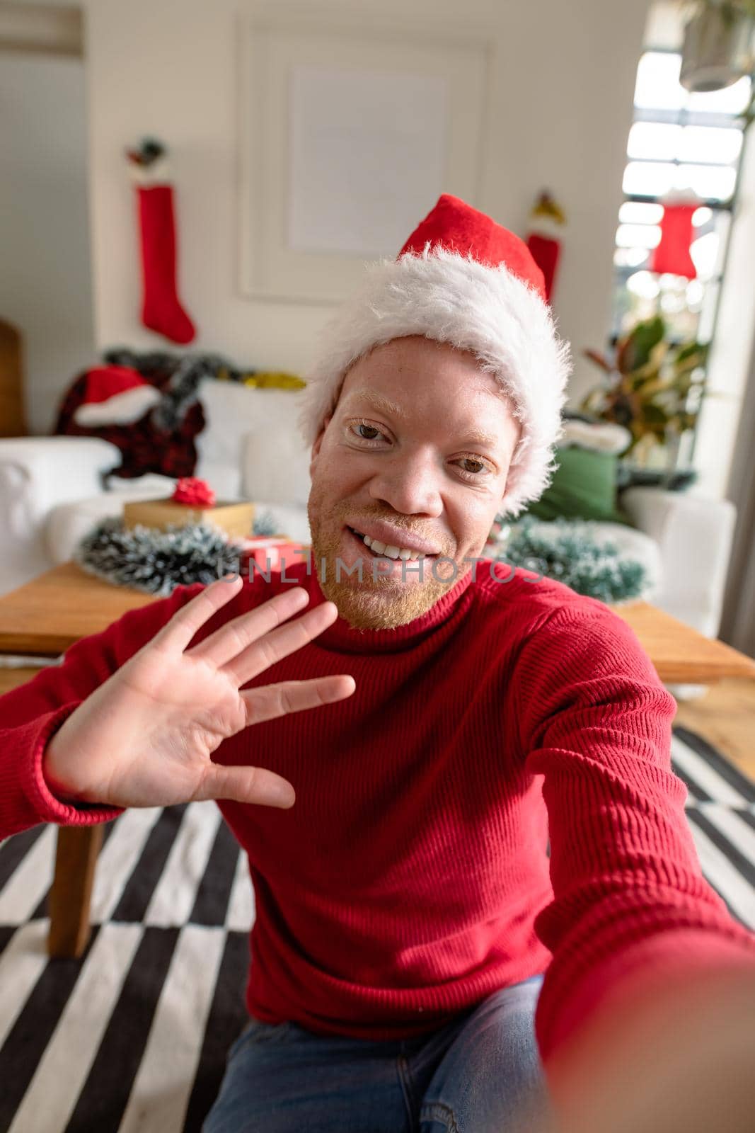 Albino african american man wearing santa hat making video call with christmas decorations by Wavebreakmedia