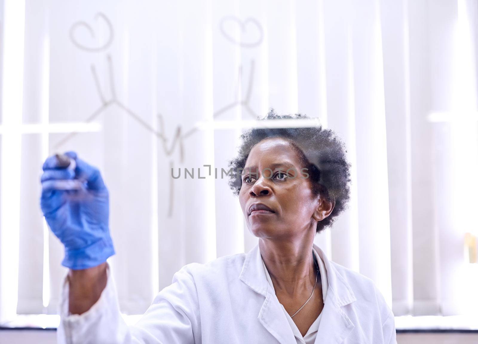 Shot of a female scientist drawing molecular structures on a glass wall in a lab.