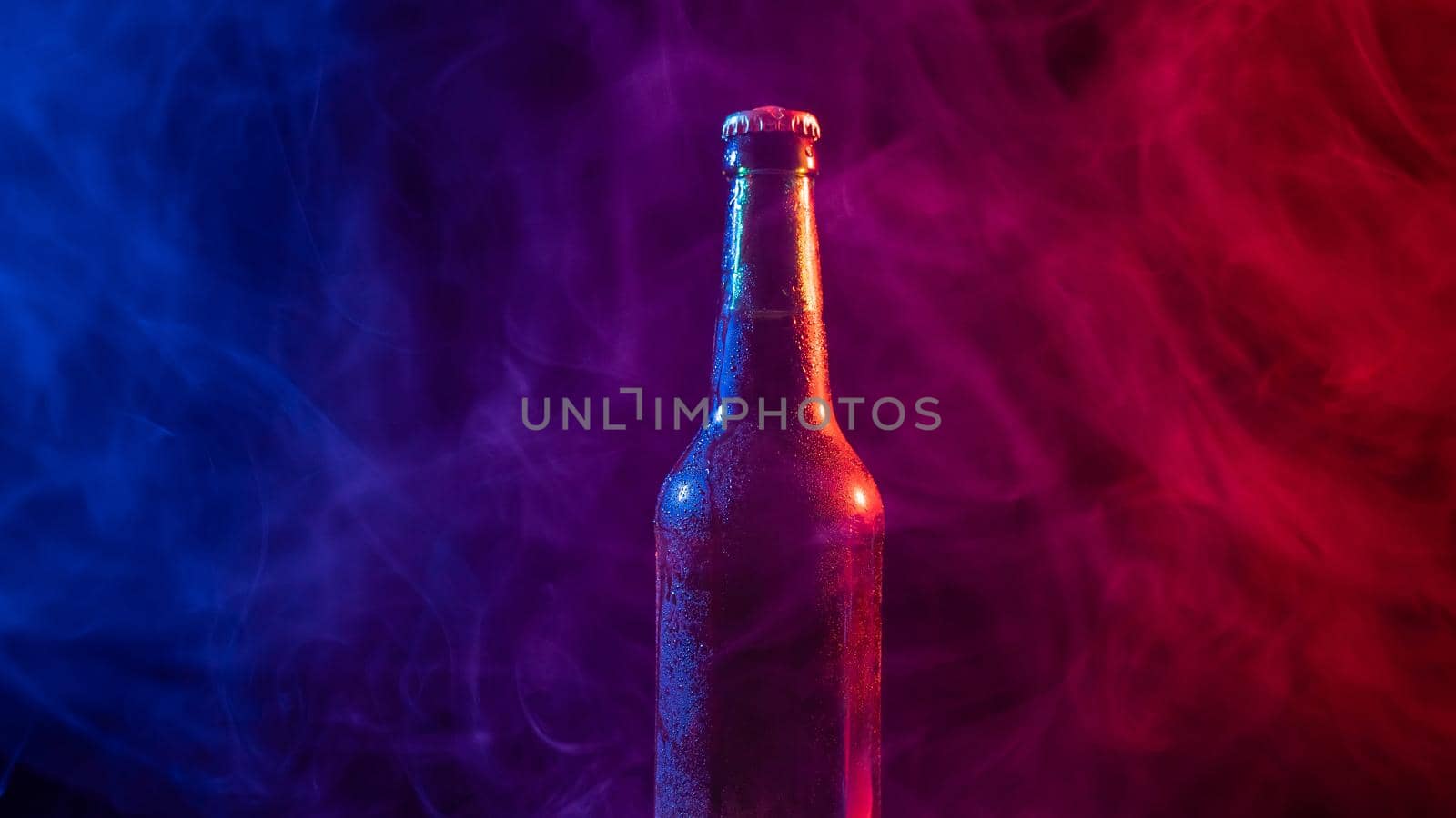 Glass bottle of beer in blue pink mist.