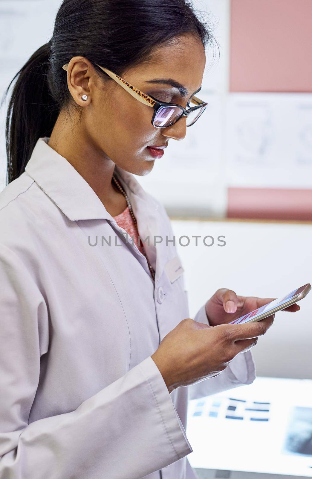 Confirming the next dental appointment with her patient. Cropped shot of a young female dentist texting on her cellphone in her office. by YuriArcurs