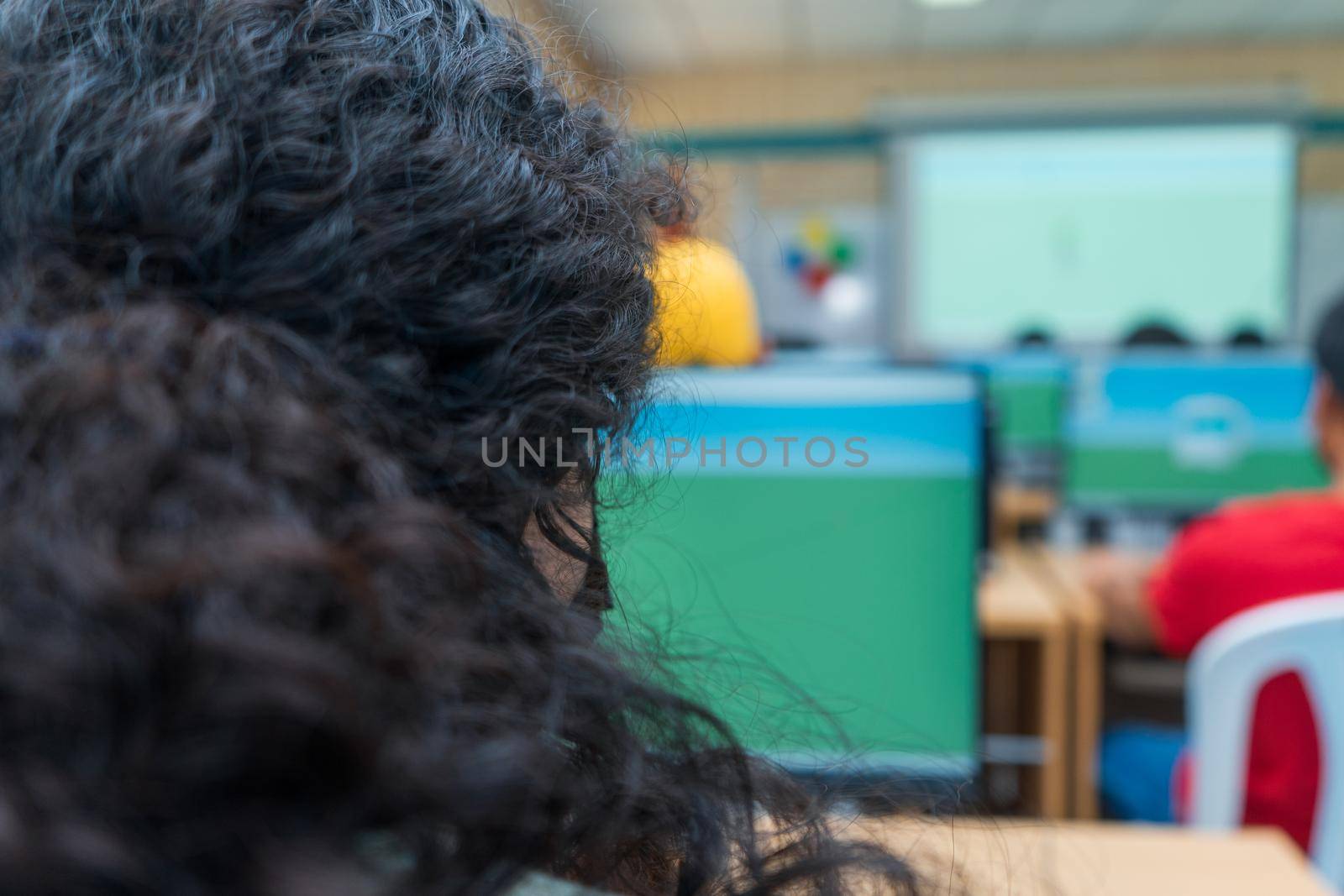 Unrecognizable woman in a classroom sitting in front of a computer in Latin America