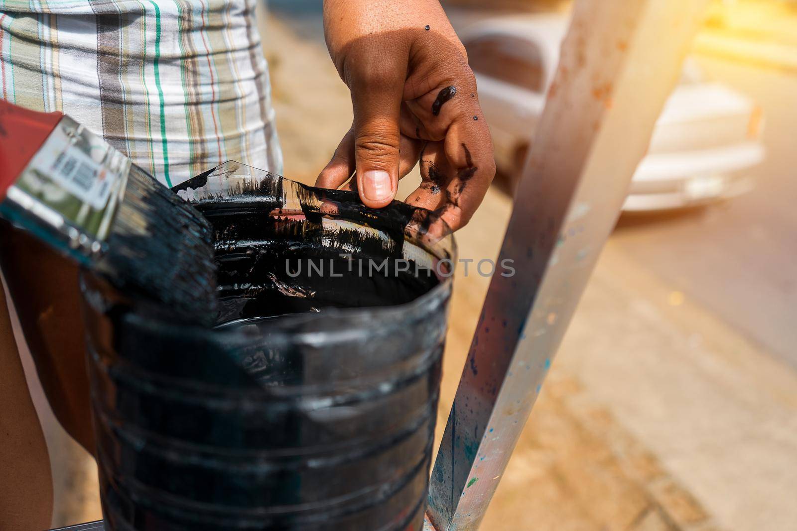 Closeup of the hands of a latin woman reloading her brush with paint in a plastic bottle to do renovations in her house