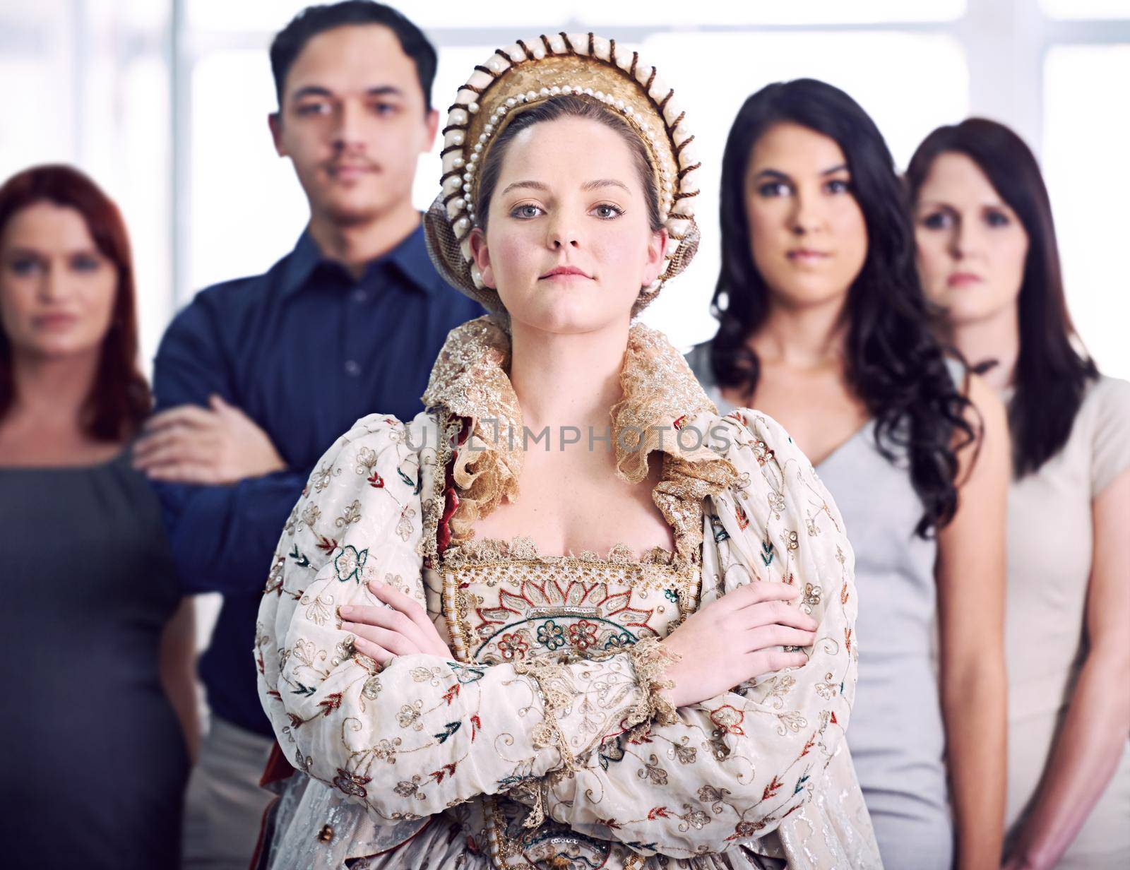 Shot of a businesswoman dressed as a queen with her colleagues in the background.