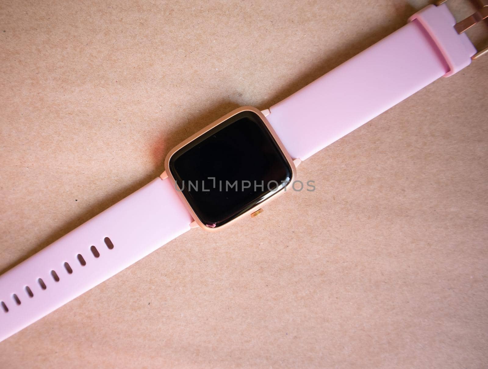 Wireless Smart Watch with Pink Strap Isolated on Brown kraft Paper Background.