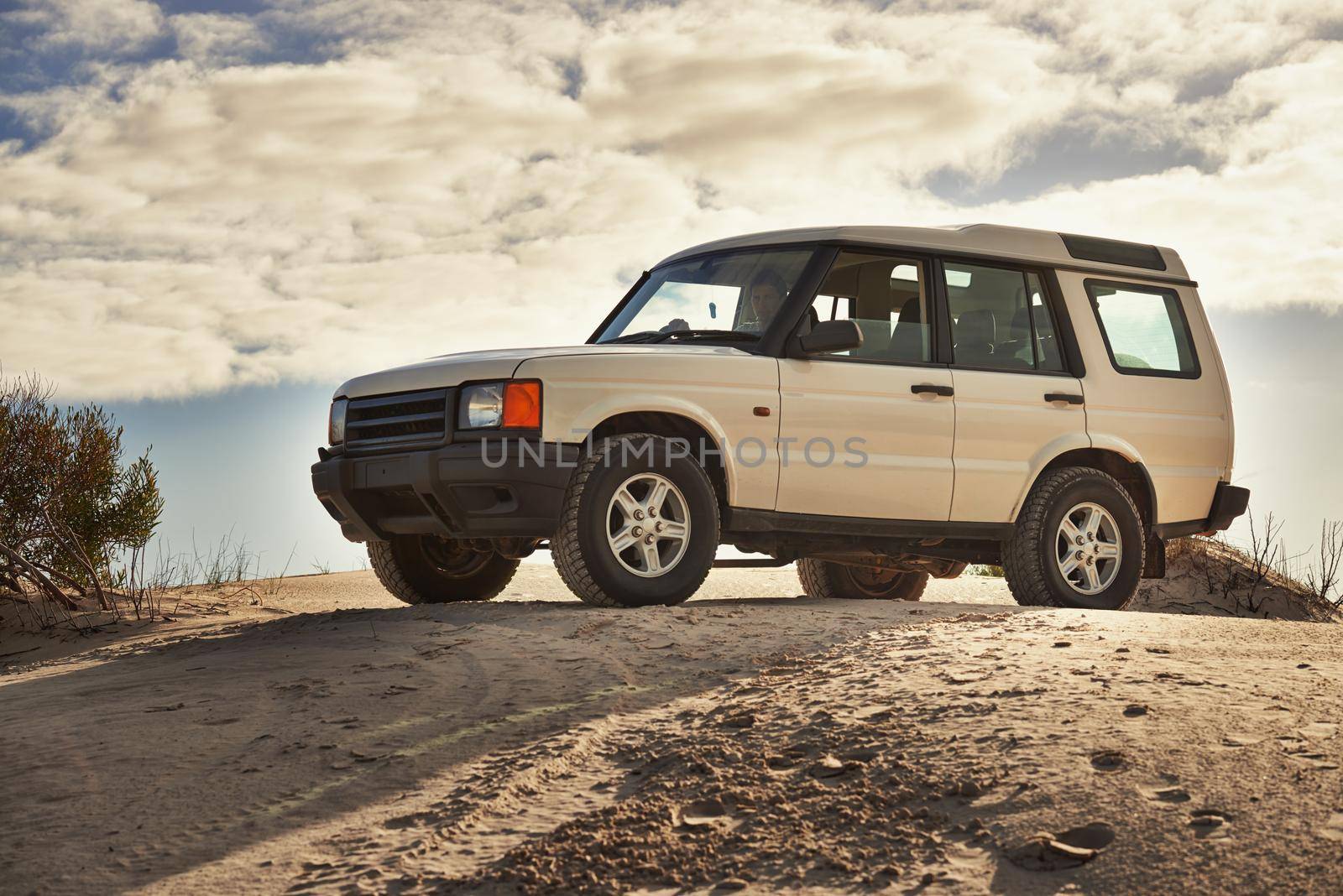 Shot of a heavy duty 4x4 driving along some sand dunes.