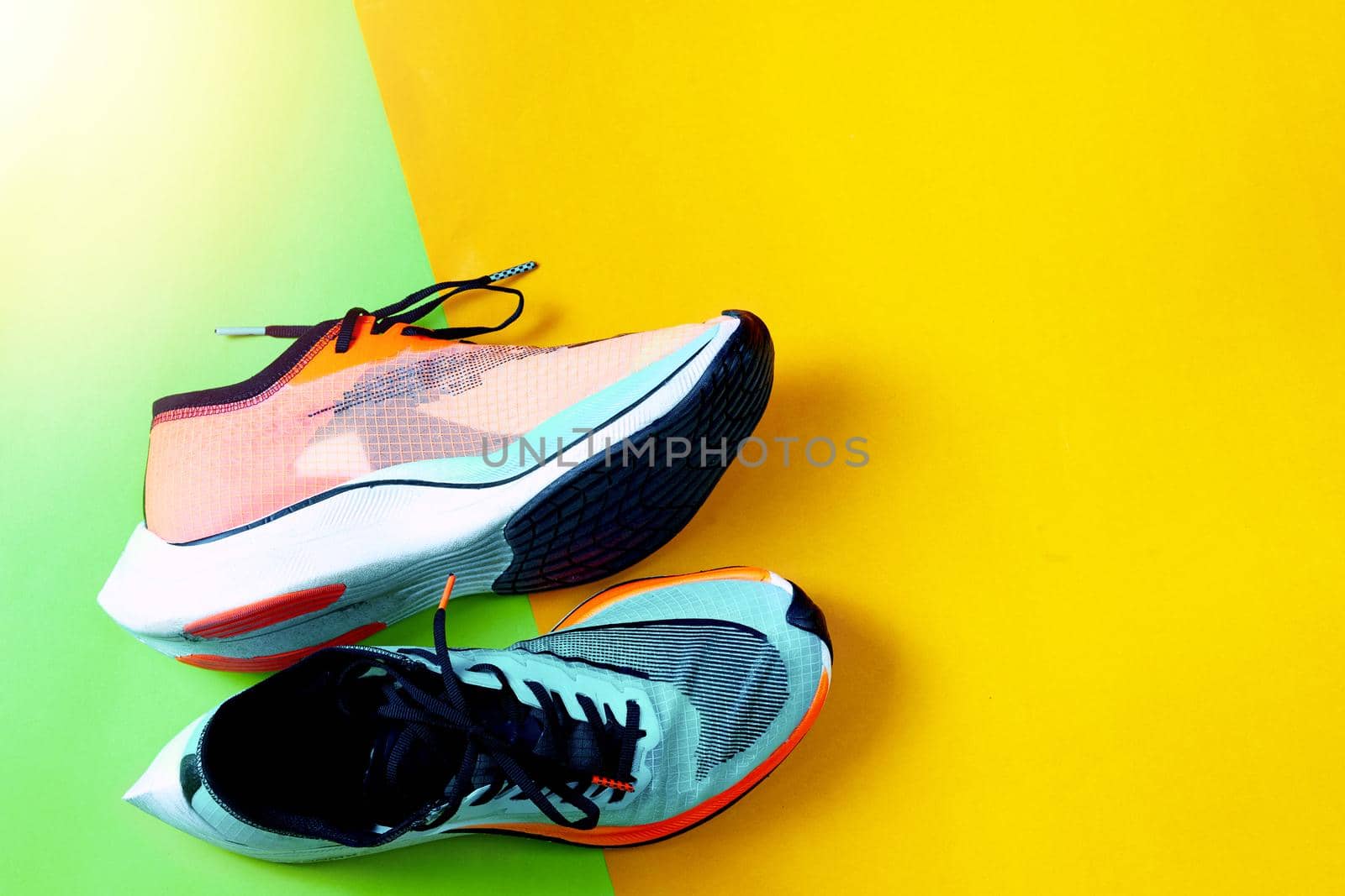 Blue and orange running shoes on color floor