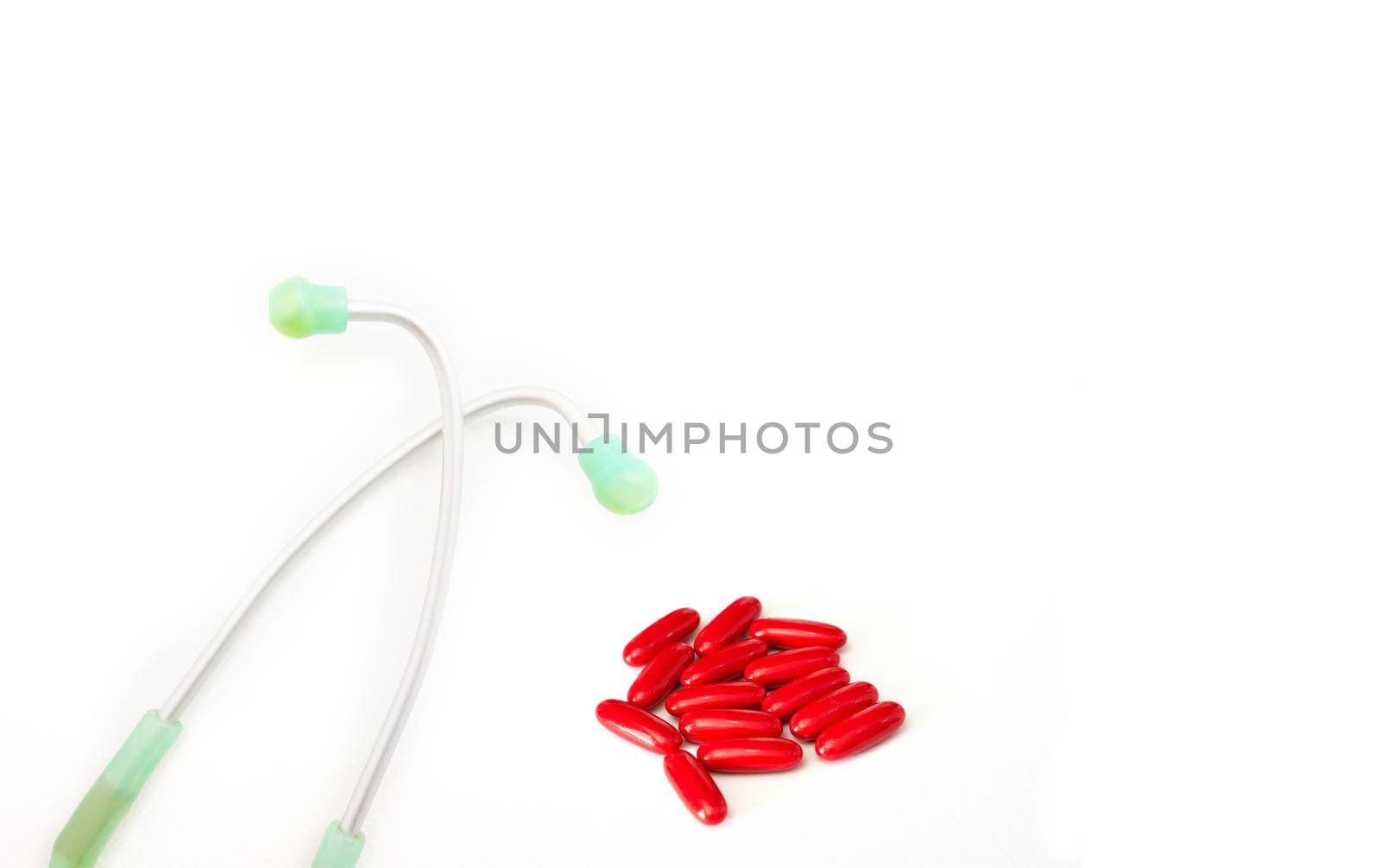 red pill and medical stethoscope on white in health background concept