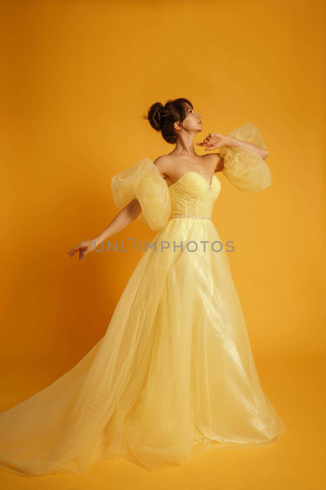 Profile portrait of a beautiful middle-aged woman in a yellow dress, her hair pulled up against a yellow background by Matiunina