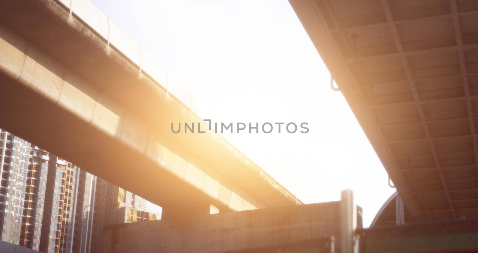 low angle view of highway overpass with sun by VacharapongW