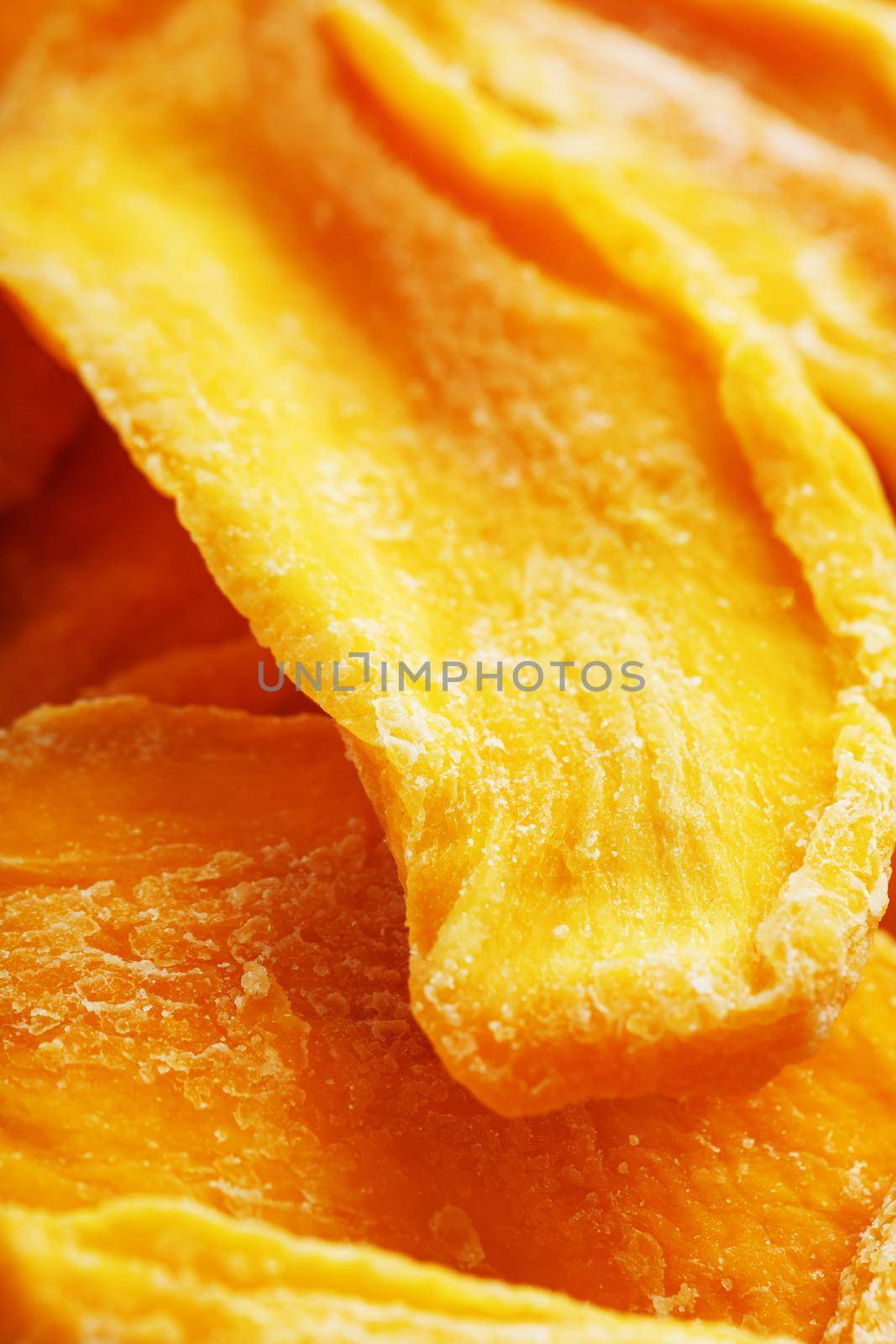 Pieces of sweet dried mango close-up as a background in full screen by AlexGrec