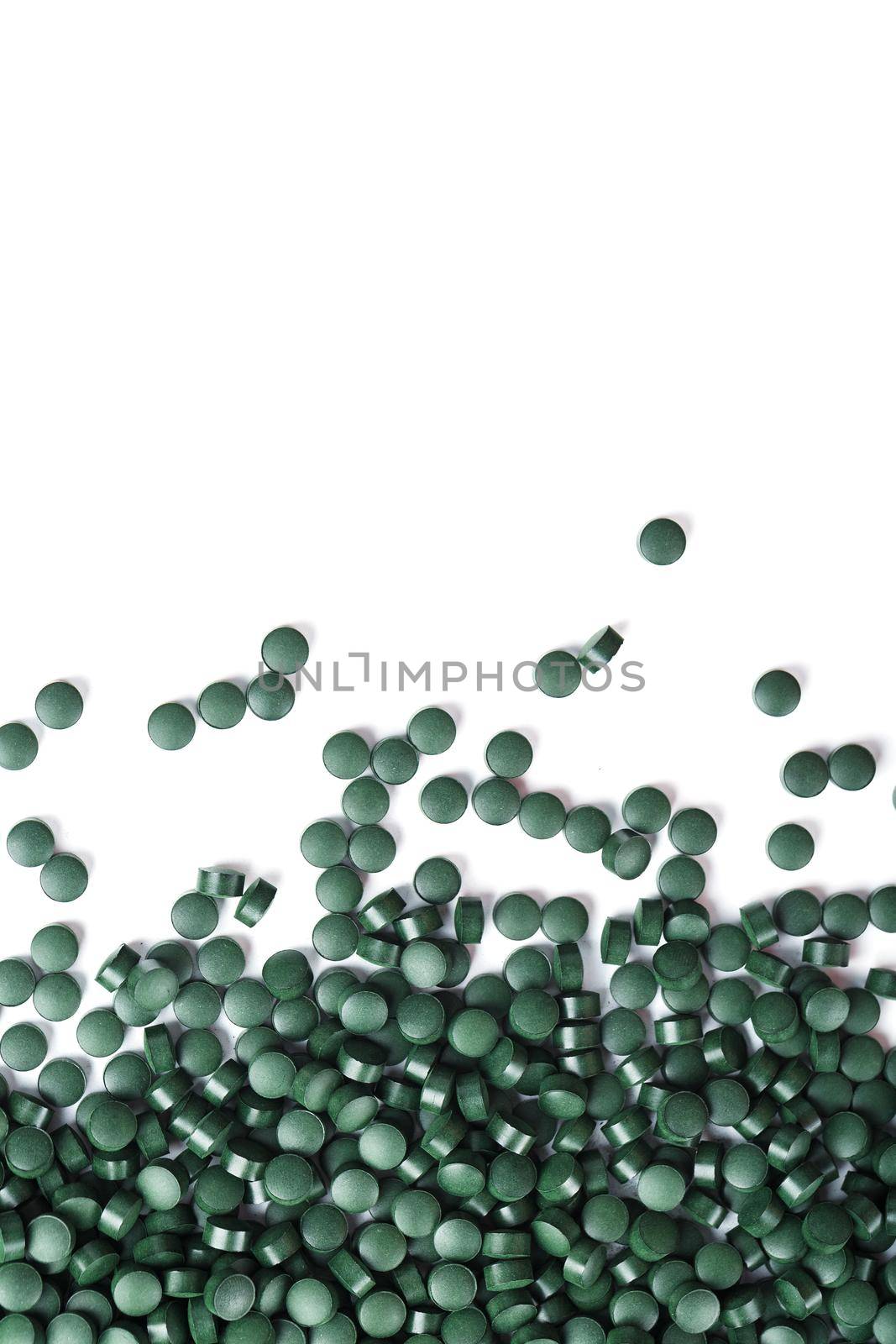 Vegetarian vitamins from Spirulina are scattered on a white background by AlexGrec
