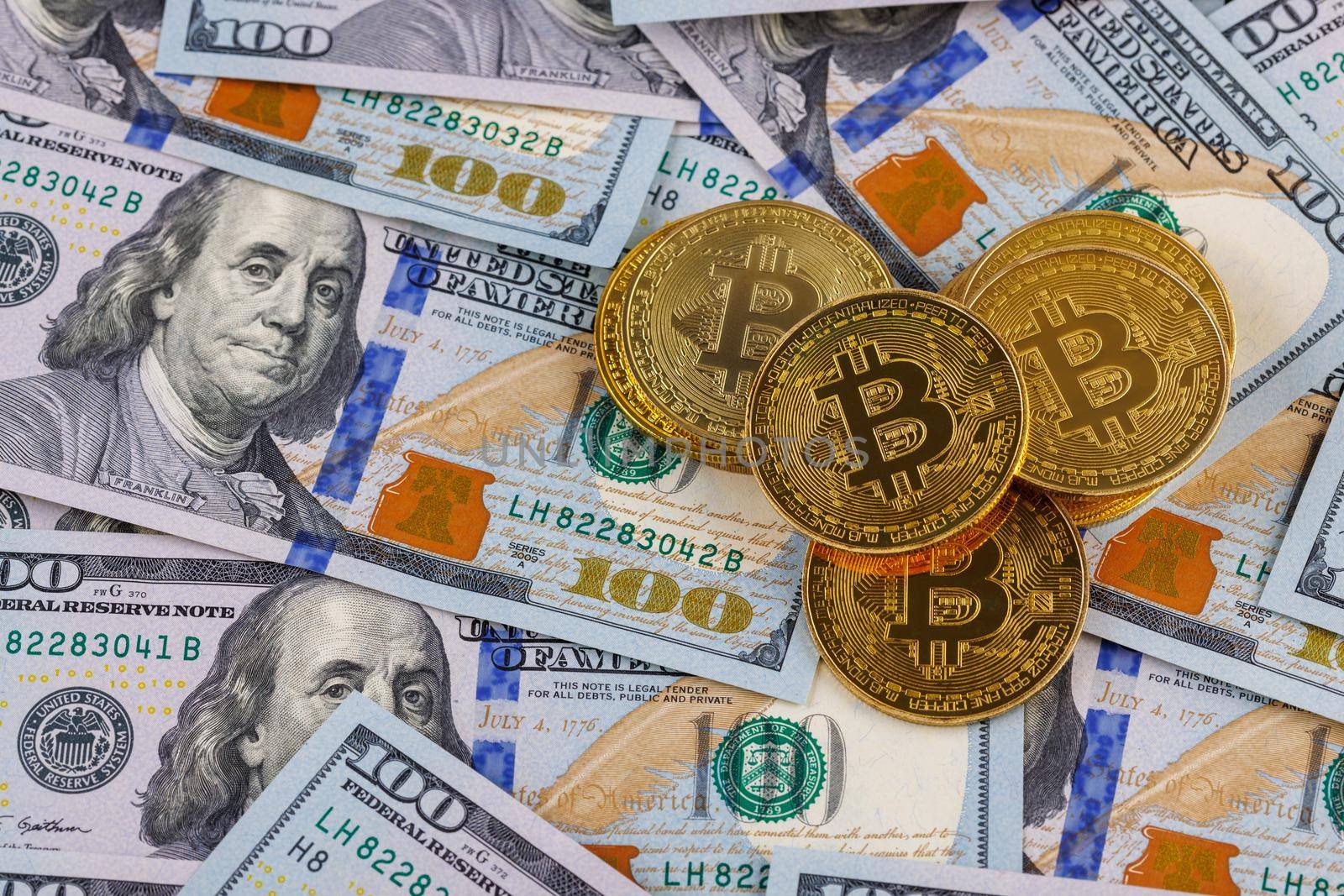 yellow bitcoin coins scattered over US dollar paper banknotes, cryptocurrency and fiat money exchange concept