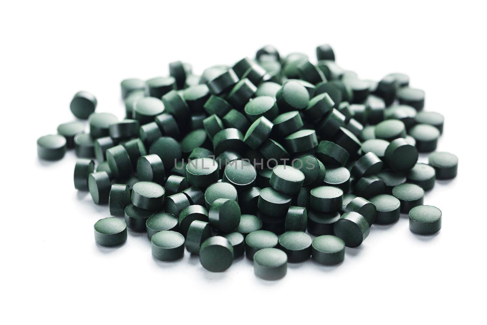Vegetarian vitamins from Spirulina are scattered on a white background with free space