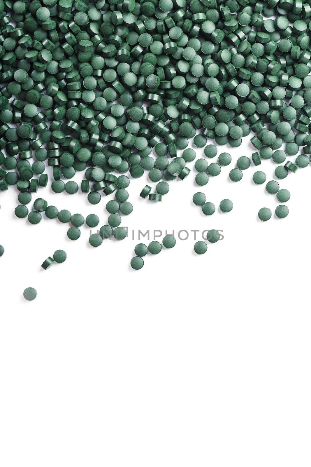 Green tablets made of natural organic spirulina on a white background with free space