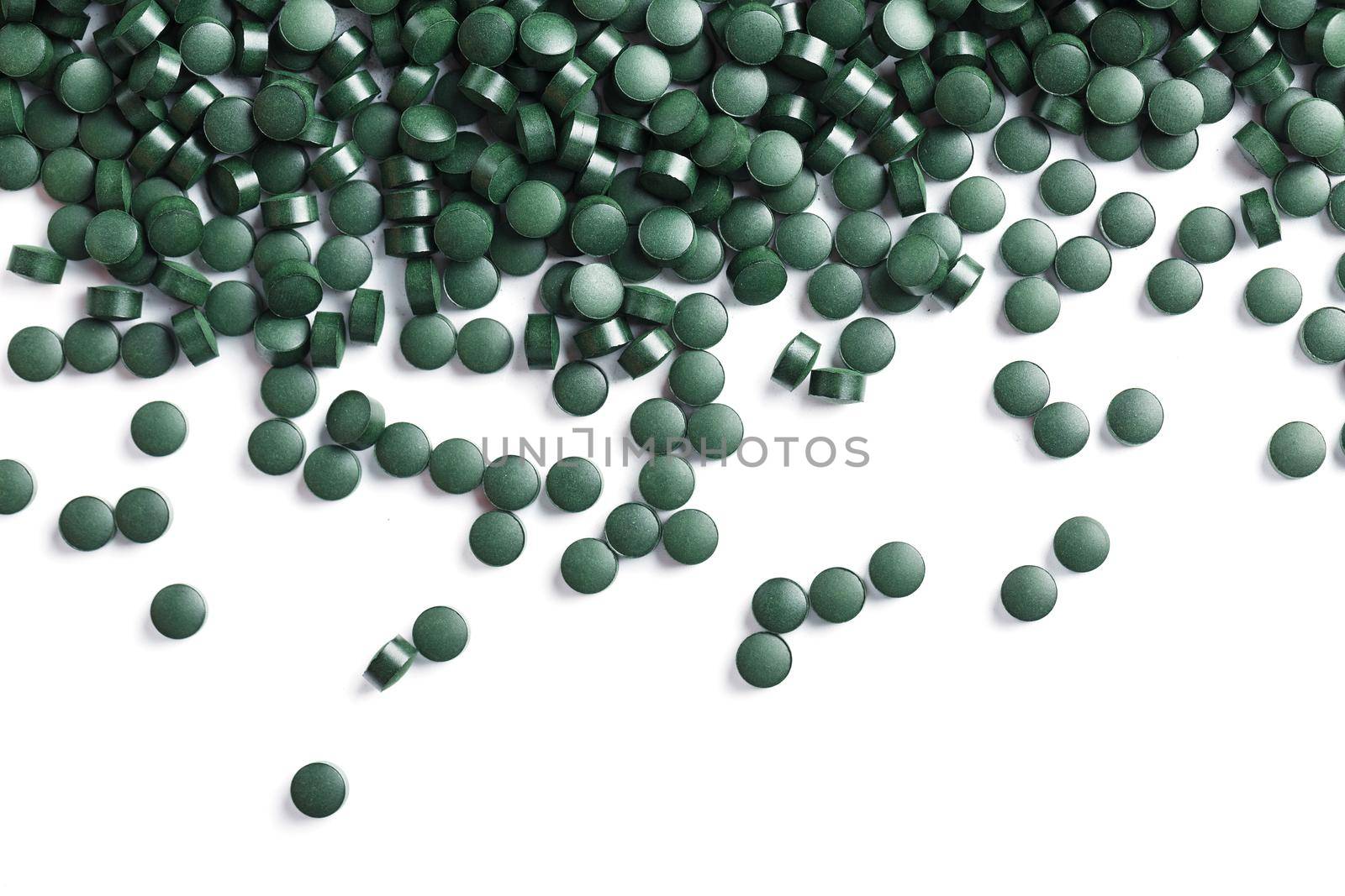 Vegetarian vitamins from Spirulina are scattered on a white background with free space