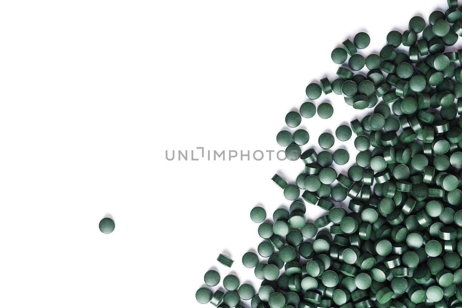 Vegetarian vitamins from Spirulina are scattered on a white background with free space