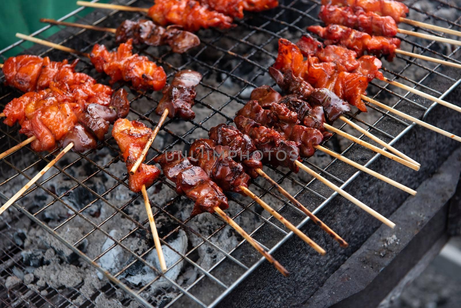 Grilled chicken sauce is a Thai barbeque food by chicken and sauce cooking on charcoal with flames at Thai street food market