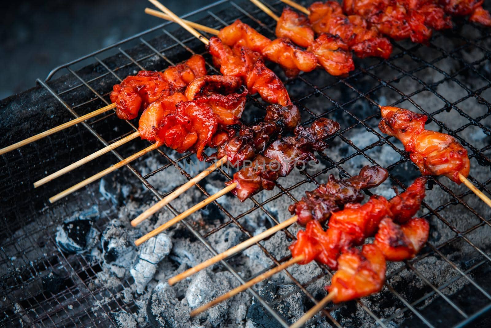 Grilled chicken sauce is a Thai barbeque food by chicken and sauce cooking on charcoal with flames at Thai street food market