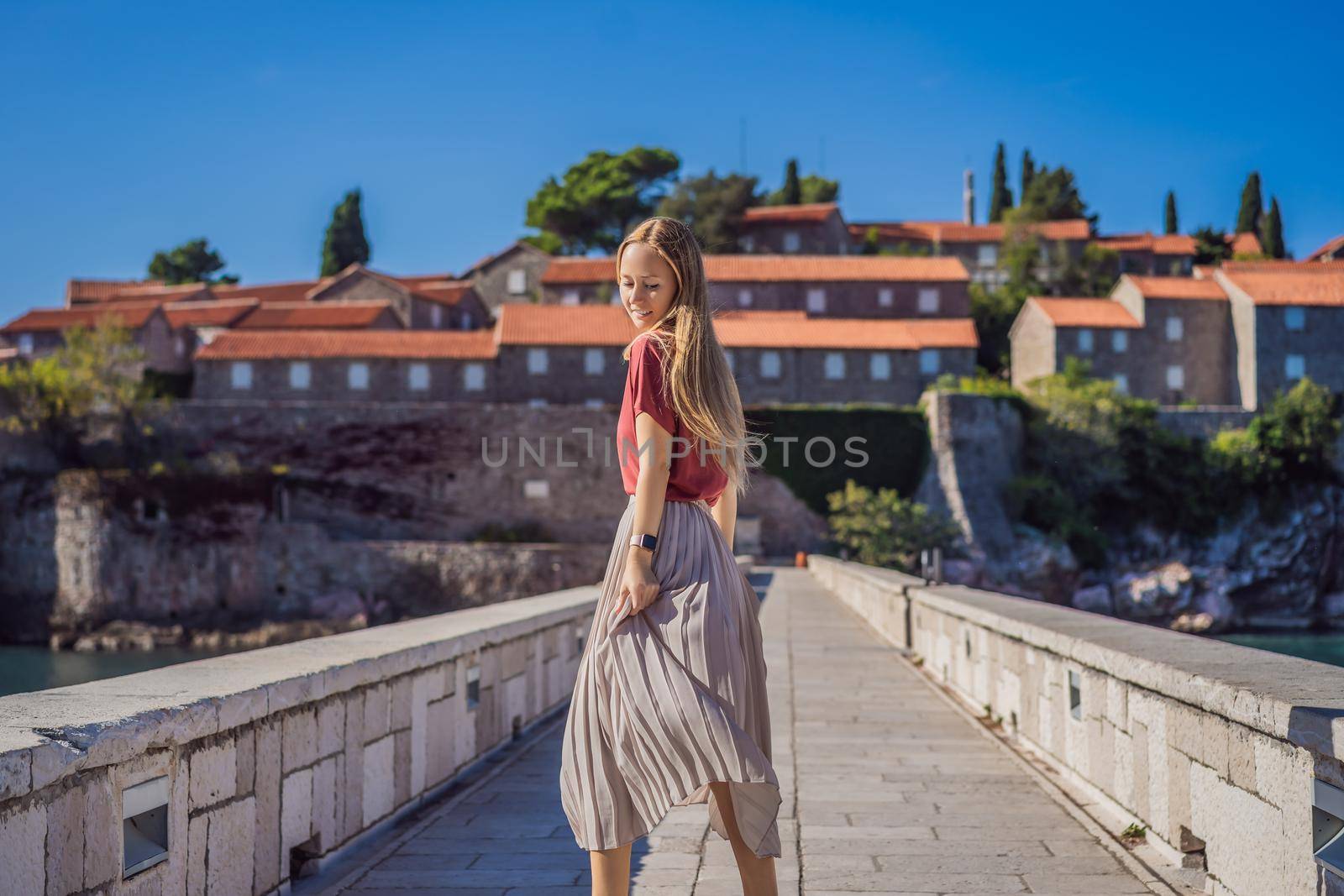 Woman tourist on background of beautiful view of the island of St. Stephen, Sveti Stefan on the Budva Riviera, Budva, Montenegro. Travel to Montenegro concept.