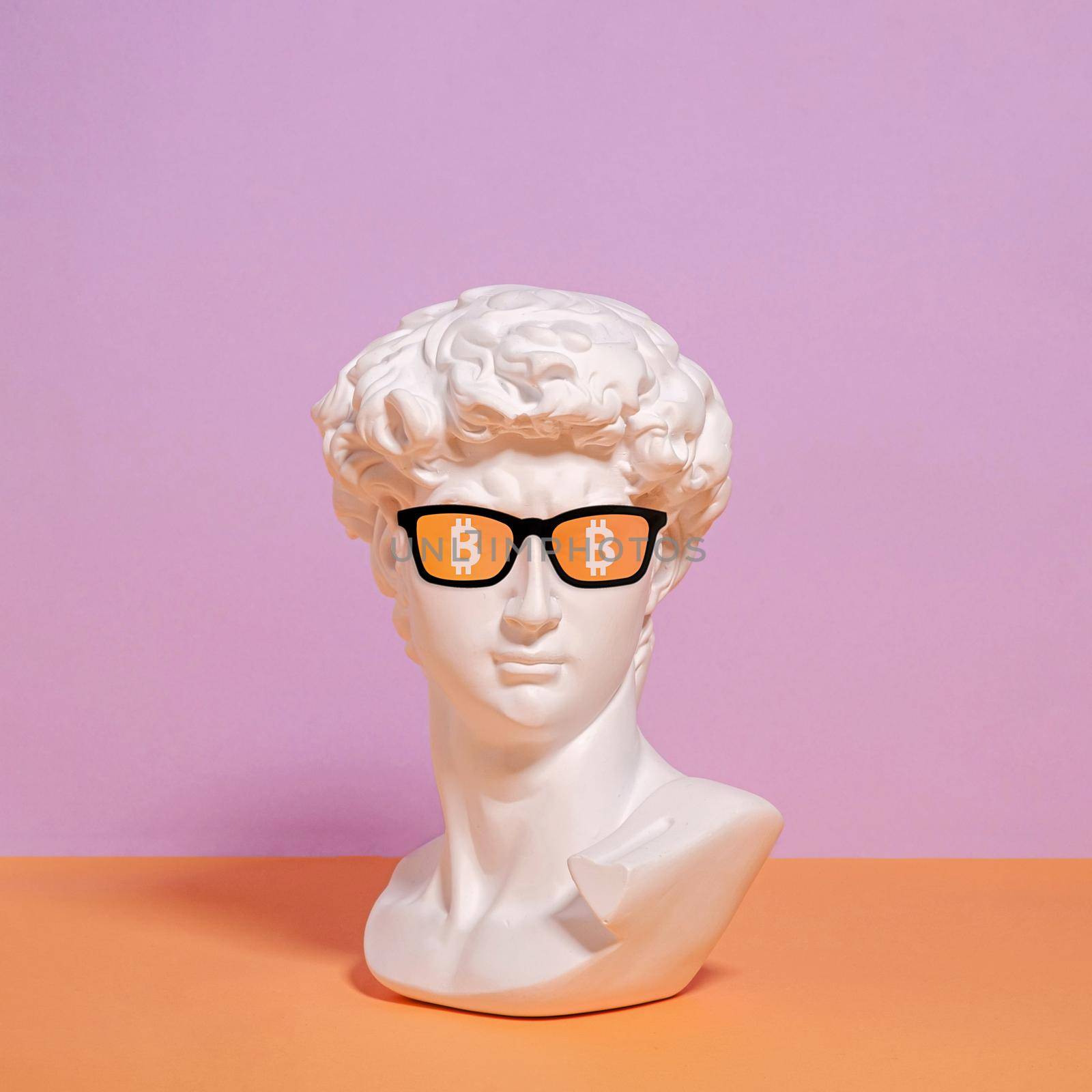 A statue of a bust of Roman David in sunglasses and a symbol of bitcoin. Innovative money blockchain and cryptocurrency on the Internet.