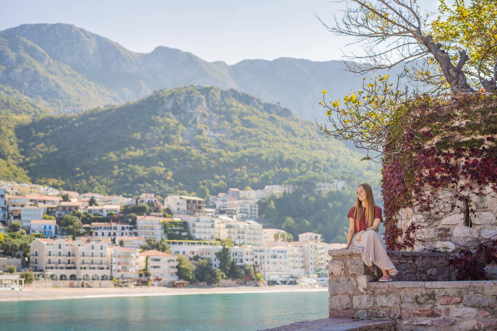 Woman tourist on background of beautiful view of the island of St. Stephen, Sveti Stefan on the Budva Riviera, Budva, Montenegro. Travel to Montenegro concept.